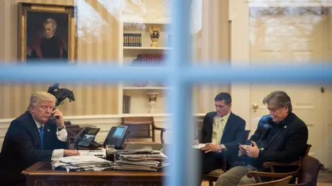 Getty Images 2017 年，史蒂夫·班农在椭圆形办公室里坐在时任总统唐纳德·特朗普和迈克尔·弗林将军对面。
