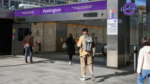 Getty Images A file image showing people walking under purple signage and an Elizabeth Line roundel towards escalators at an entrance to Paddington Station