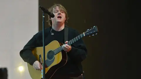 Lewis Capaldi performs onstage with an acoustic guitar