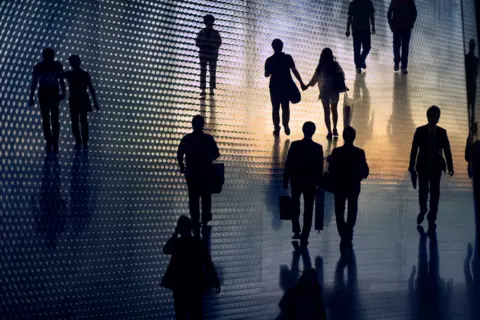 Getty Images People in sillouette are pictured walking in a sunset.