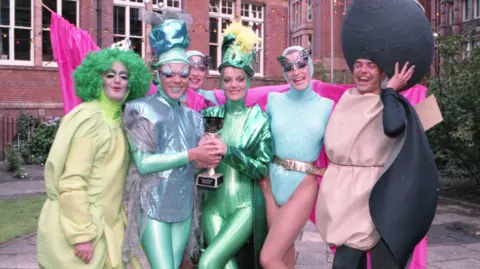 Stuart Rhoades A group of people dressed in different brightly coloured outfits are posing for a picture in the Gay Village. 