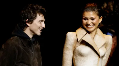 Reuters Timothee Chalamet and Zendaya standing and smiling on stage