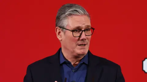 PA Media PM Sir Keir Starmer stands in front of a red background during a visit to Horntye Park Sports Complex in St Leonard's on Sea.