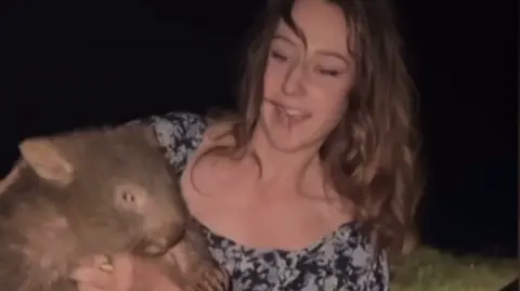 Screenshot of Sam Jones' Instagram video, which shoes her holding a baby wombat on a road at night.