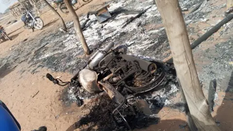 Zakari Kontagora A burnt out motorbike lying on its side.