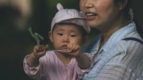 EPA A woman walks with a baby on a street in Shanghai, China, 31 May 2021.