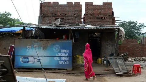 Getty Images A woman walks past a closed down alcohol shop close to the Bihar border