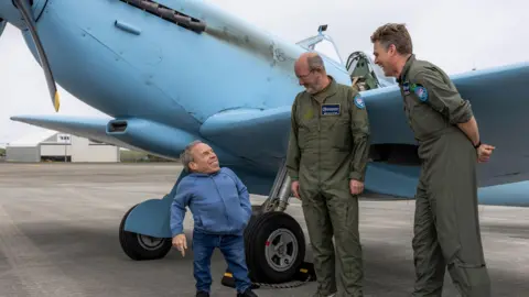 Royal Air Force Warwick Davis on the left stood next to two of the pilots of the Spitfire.