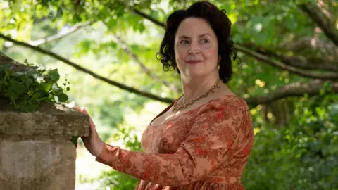 Ruth Jones in green countryside as Mrs Bennett in the BBC production of The Other Bennet Sister