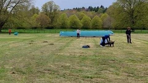 Volunteers with rakes and wheelbarrows at the cricket club
