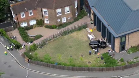 PA Media Aerial view of the scene of the black Land Rover crashed into the school playground with police and equipment strewn on the ground