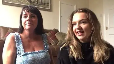 Anna and her daughter sitting in a living room smiling into the camera.