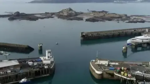 An elevated view of St Helier Harbour showing quaysides and boats. The water is calm.