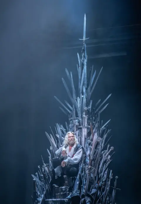 Johan Persson Michael Shaeffer (King Aerys II Targaryen) seated on the Iron Throne, made from dozens of protruding swords, in a scene from Game of Thrones: The Mad King.
