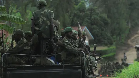 Democratic Republic of Congo government soldiers, in uniform, ride at the back of a military truck, on November 25, 2012 in Minova