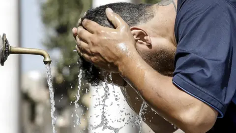 EPA A man cools off in Saint Peter's Square, Rome, during a heatwave, 3 August 2017