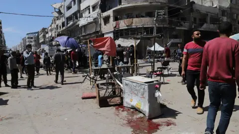 Palestinians look at the aftermath of reported Israeli strikes on a restaurant and a market place on al-Wahda Street, al-Rimal neighbourhood, Gaza City, northern Gaza (7 May 2025)