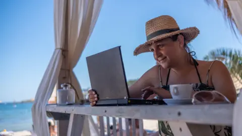 Lady at a laptop next to the beach