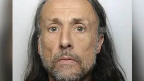 Dyfed-Powys Police Richard Jones with grey beard and long hair looking directly at the camera