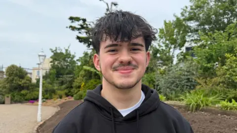 Diogo Baptista is pictured wearing a black top and white t-shirt. He has black hair.