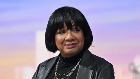 Diane Abbott is pictured wearing a black jacket and jumper on a BBC set.