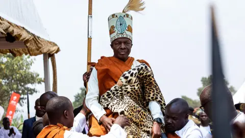 AFP A man carries Kabaka (King) Ronald Muwenda Mutebi II on his shoulders during his 30 year coronation at his palace in Mengo, Kampala, on July 31, 2023.