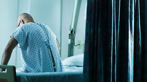 Getty Images Man sitting on a hospital bed