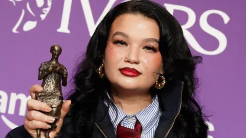 PA Lola Young holding up her award trophy