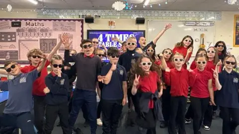 Children from Ecclesfield Primary School singing times tables to K-Pop songs wearing sunglasses.