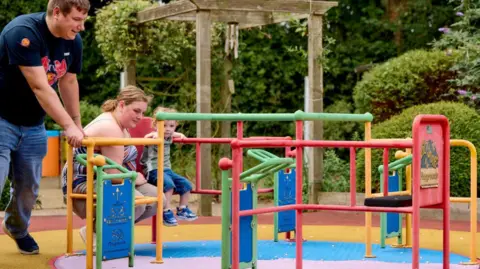 Child and two adults on new roundabout 
