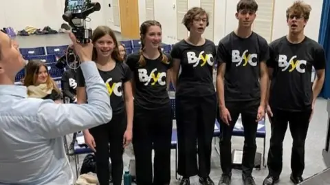 Members of the Brighton Festival Youth Choir being filmed by BBC South East at Brighton Aldridge Community Academy, Brighton. The five singers pictured were the members of the choir who all sang on the original recording of the Wander to Wonder soundtrack.  