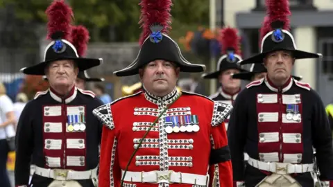 EPA Three members of the Hillsborough Fort Guard - wearing uniform and distinctive feathered hats - stand at attention outside Hillsborough Castle