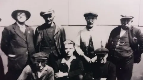 The Porthmadog Maritime Museum A black and white photo of the crew of the ship in the 1930s. Seven members, all wearing hats and waistcoats.