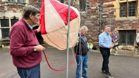 Three men stood around a hot air balloon replica at Berkeley Castle