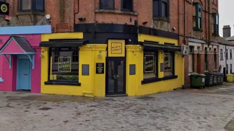 A bar on a street corner, painted in yellow and black with branding on the windows and doors reading "North Street".