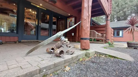 A propeller and crankshaft sitting on a patio in front of the Glenforsa Hotel