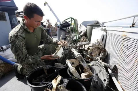 AFP An American officer inspects fragments of a plane on the deck of the French FS Pluton M622 navy de-mining ship