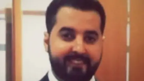 Supplied Bader Alomair smiles at the camera - he has dark hair and a dark beard, and appears to be wearing a white shirt and dark suit