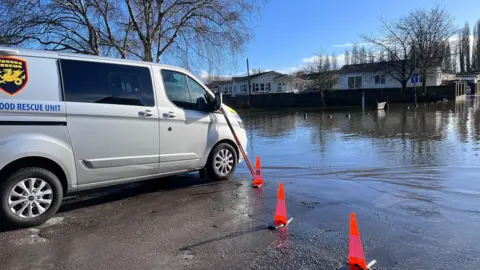 A rescue van parked at the edge of the flooded area.