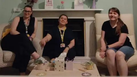Hey Endo! Three women wearing black sit in a living room. 