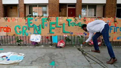 AFP A man leaving flowers at a Grenfell Tower tribute