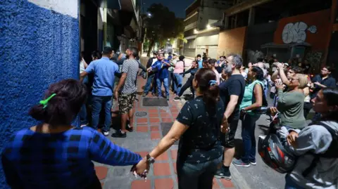 Getty Een groep mensen houdt elkaars hand vast uit protest tegen het mogen tellen van stemmen tijdens de presidentsverkiezingen van 28 juli 2024 in Caracas, Venezuela. 