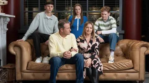 Lime Pictures The Hutchinson family - featuring parents Diane and Tony Hutchinson with three of their children - are sat on a couch for this posed promotional image. 