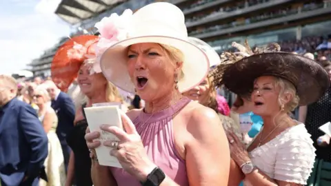 NEIL HALL/EPA/Shutterstock A woman cheers on her horse on the first day of Royal Ascot.