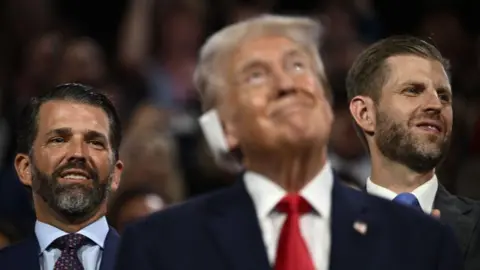 Getty US former President and 2024 Republican presidential candidate Donald Trump looks on as his sons Donald Trump Jr. (L) and Eric Trump stand behind him during the first day of the 2024 Republican National Convention 