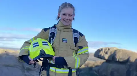 Lou Needham Lou Needham posing in her firefighter kit