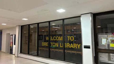 Shariqua Ahmed/BBC Exterior of Bretton Library - glass window with a yellow "Bretton Library" sign 