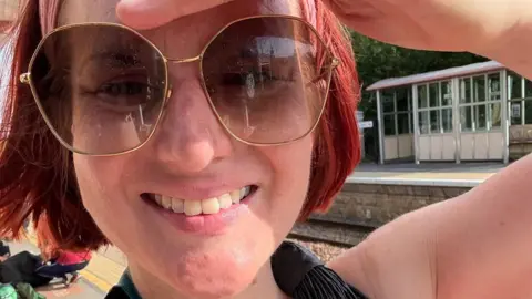 Gill Capewell, a woman with a red bob haircut wearing sunglasses