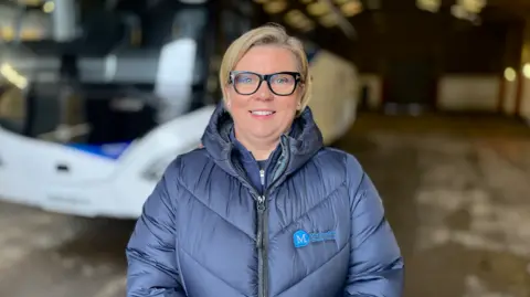 PA Media Caroline McComb, with blonde hair and glasses, wearing a blue jacket