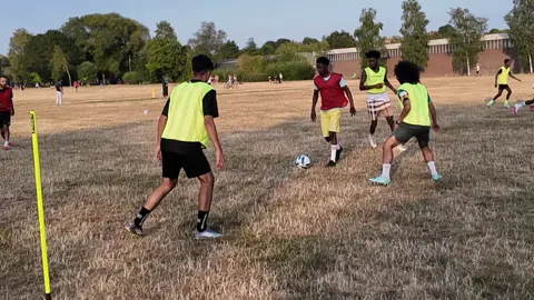 Footballers training by playing a game on dry grass.